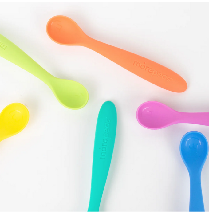 Several silicon baby spoons on white background in orange, green, blue, purple, and yellow