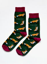 Load image into Gallery viewer, Forest green socks with light maroon cuffs, heels and toes. yellow/orange foxes with white chest/chin and tail tip line the socks. The name Bare Kind is written in white under the first row of foxes. 