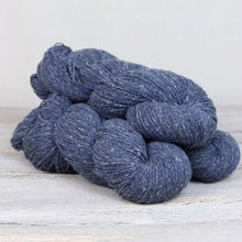 Load image into Gallery viewer, 3 skeins of dark navy blue yarn with flecks of yellow, green, and white throughout on white background.