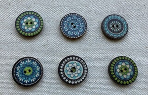 Image of 6 round green/blue/black buttons with mandala patterns on them. Each has two holes in middle