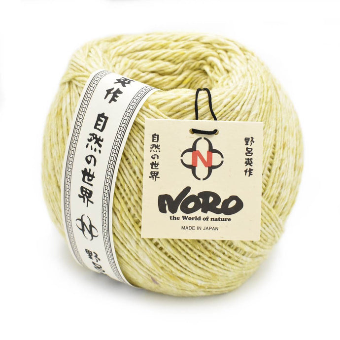 Close up of Noro Yarn in Moegi shade; Appears light yellow/green with white throughout; Shown from side with paper label wrapped around left outside edge in black and white with Japanese characters running up and down; Reads 