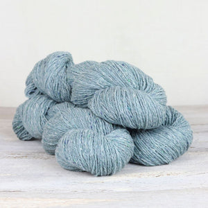 3 skeins of light blue yarn with flecks of white on white background.