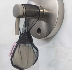 Small black mesh bag reads "Conditioner" on small pink label and contains white bar of conditioner soap as it hangs on shower handle