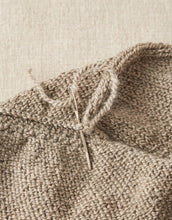 Load image into Gallery viewer, A bent tip tapestry needle threaded with tan yarn from the tail end of a knitted project working back into seam of project