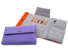 Load image into Gallery viewer, Large gray knitting needle project pouch unfolded onto white background with smaller purple pouch buttoned up in front. Several pairs of needles stick out of middle gray pouch pocket with empty pockets to right side and orange snap button strip on left side