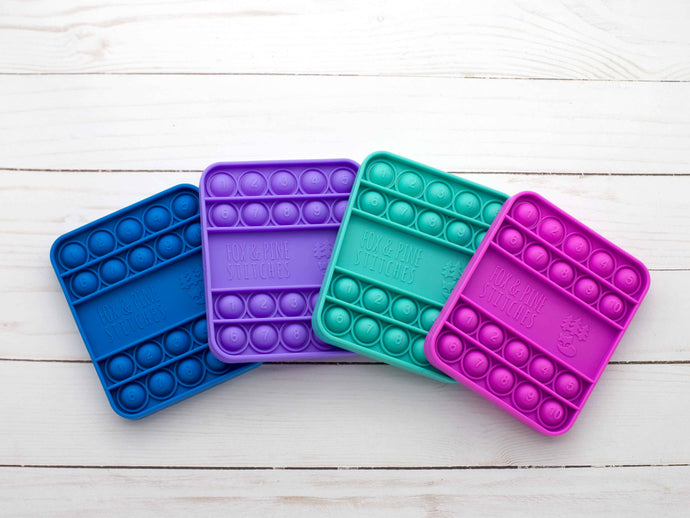 Four colorful pop-it fidget toys on a wooden surface