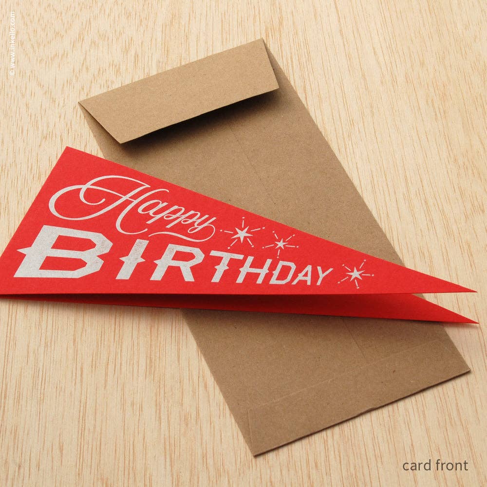 Red birthday pennant card with brown envelope on a wooden surface