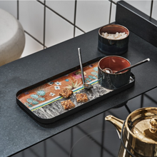 Load image into Gallery viewer, Image of rectangular food tray on gray table top. Tray features colorful images of plants and flowers in blues, oranges, pinks, yellows, and gray. Gray and copper colored mug sticks with spoon sticking out on tray. Second mug sits to right of tray on table with gold colored tea pot in front of tray on table top