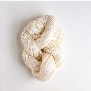 Cream colored yarn twisted up on white colored background