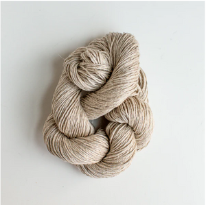 Tan colored yarn twisted up on white background