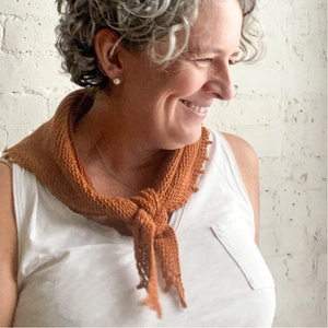 Image of a woman smiling and wearing a small russet colored knitted bandana