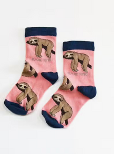 Pink socks with navy blue cuffs, heels and toes. Tan sloths on branches line the socks. The name Bare Kind is written in light grey under the first row of sloths.
