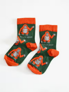Forest green socks with deep orange cuffs, heels and toes. Deep orange orangutans with light grey faces, bellies, and hands line the socks. The name Bare Kind is written in light grey under the first row of orangutans.