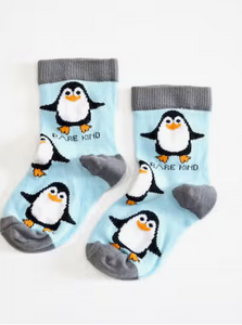 Sky blue socks with grey cuffs, heels and toes. Black and white penguins with orange beaks line the socks. The name Bare Kind is written in black under the first row of penguins.