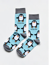Load image into Gallery viewer, Sky blue socks with grey cuffs, heels and toes. Black and white penguins with orange beaks line the socks. The name Bare Kind is written in black under the first row of penguins.