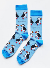Load image into Gallery viewer, Light blue socks with darker blue cuffs, heels and toes. Black and white puffins with colored beaks line the socks. The name Bare Kind is written in grey under the first row of puffins.