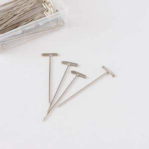 Serveral needles from clear plastic container laid out on white background