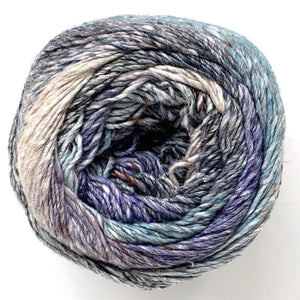 Close up of top of Noro yarn in color Hirosaki; Strands in shades of blue, purple, black, and tan spiral in circle on white background