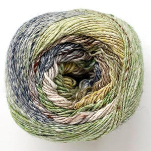 Close up of Noro yarn in color Yachimata; Strands in shades of blue, yellow, green, and brown spiral in circle on white background