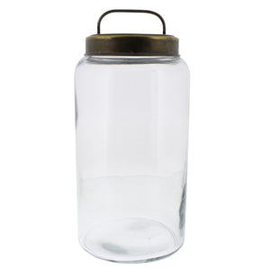 Tall glass canister jar with brass colored lid with handle on white background.