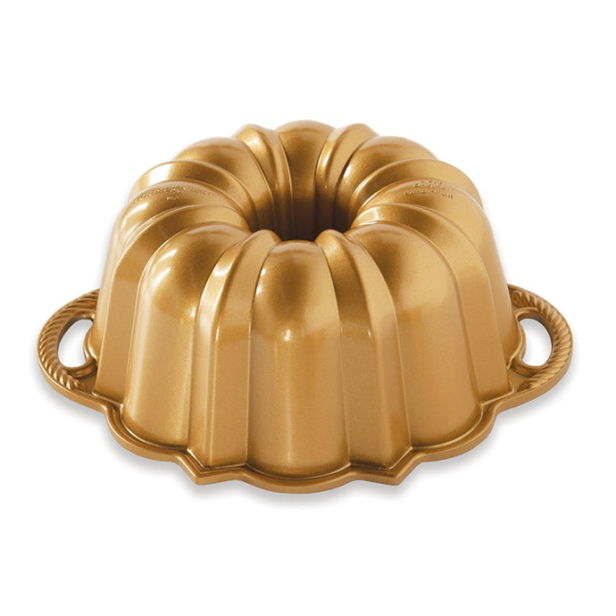 Bright gold bundt pan with 2 rope patterned handles on white background; fluted edges with rounded and pointed designs