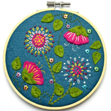 Load image into Gallery viewer, Light yellow embroidery hoop on white background with dark blue fabric in hoop. Flowers in pink, yellow, white, green, and blue cover the dark blue fabric in many different embroidery styles