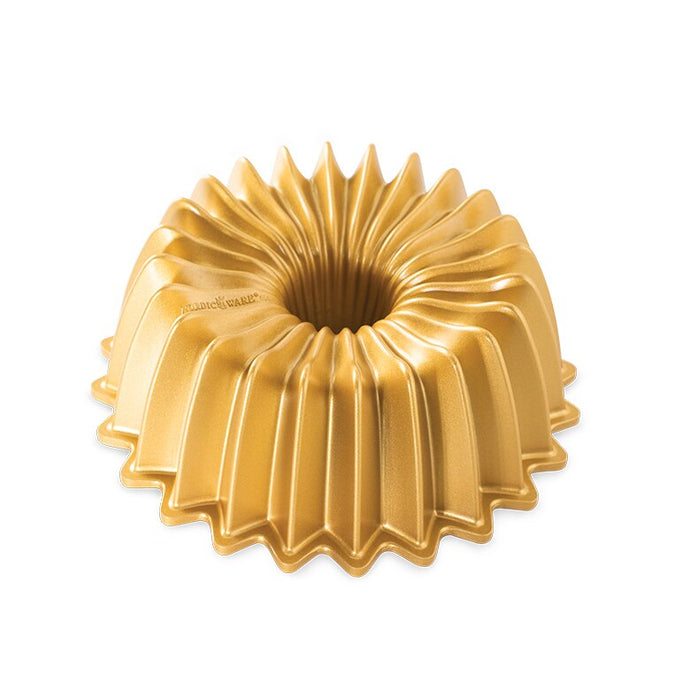 Bright gold bundt pan with fluted sides and hole in middle on white background; 