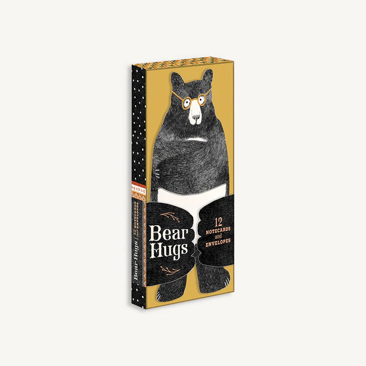 Yellow and black box of Bear Hugs notecards and envelopes with drawing of black bear wrapped in white towel with yellow glasses on sits on front of box