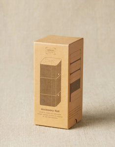 Image of small cardboard box container on light tan background; Box angled to side to show front and right of box; Front of box reads "COCO KNITS"; Image of accessory roll in middle with "Accessory Roll" text below