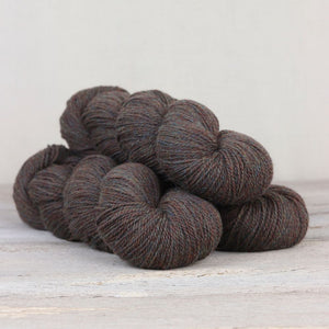 The Fibre Co. Amble yarn in color Fair Hill. Strands in shades of blue, gray, orange, and brown
