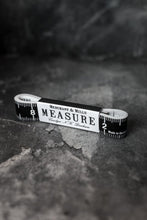 Load image into Gallery viewer, Black and white tape measurer wound up and secured in black and white Merchant &amp; Mills label