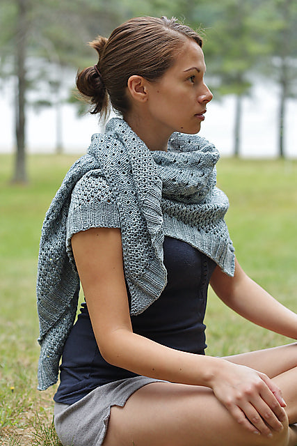 GIRL SITTING INDIAN STYLE WEARING KNITTED SHAWL AT CAMP GROUND