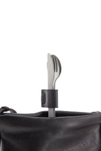 Load image into Gallery viewer, Set of silverware; knife, fork and spoon. The three utensils are held together by a black clasp as they sit standing upright in a black bag.