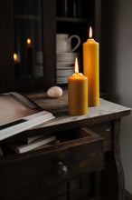 Load image into Gallery viewer, Two mustard yellow candles of differing heights sit lit on wooden table