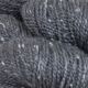 Close up image of Plume colored yarn hank; Dark gray hue with white speckles throughout