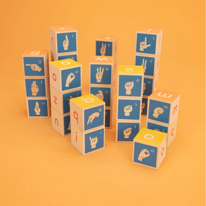 Uncle Goose American Sign Language Blocks in blue, yellow, and tan in stacks on orange background. Block depict letters of the alphabet and images of hands performing the signs for each letter