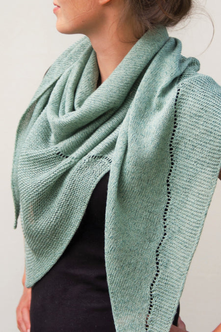 Image of woman in light blue/green knitted scarf looking to the side on a white background
