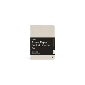 Small light gray/tan  journal on white background with black paper wrap covering middle section; Black wrap reads "KARST" "Stone Paper Pocket Journal" "A6" in white on right side; Small black "K" stamped in bottom right corner of cover