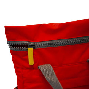 Close up on stop of red ORI bag with yellow zipper tab on white background