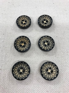 Image of 6 black white round buttons with floral design in middle. Each have four holes in middle.
