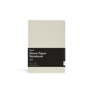 Smooth light gray/ tan journal; Large black rectangular paper wrap half way down reads "KARST" "Stone paper Notebook "A5" on right side; Small "K" stamped in bottom right side corner