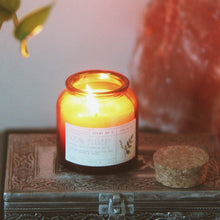 Load image into Gallery viewer, Balsam scented candle. Red/orange glass bottle with a cork top, white label with black lettering.